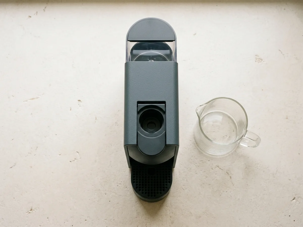 Une machine à capsules vue du dessus, avec une carafe en verre vide à côté